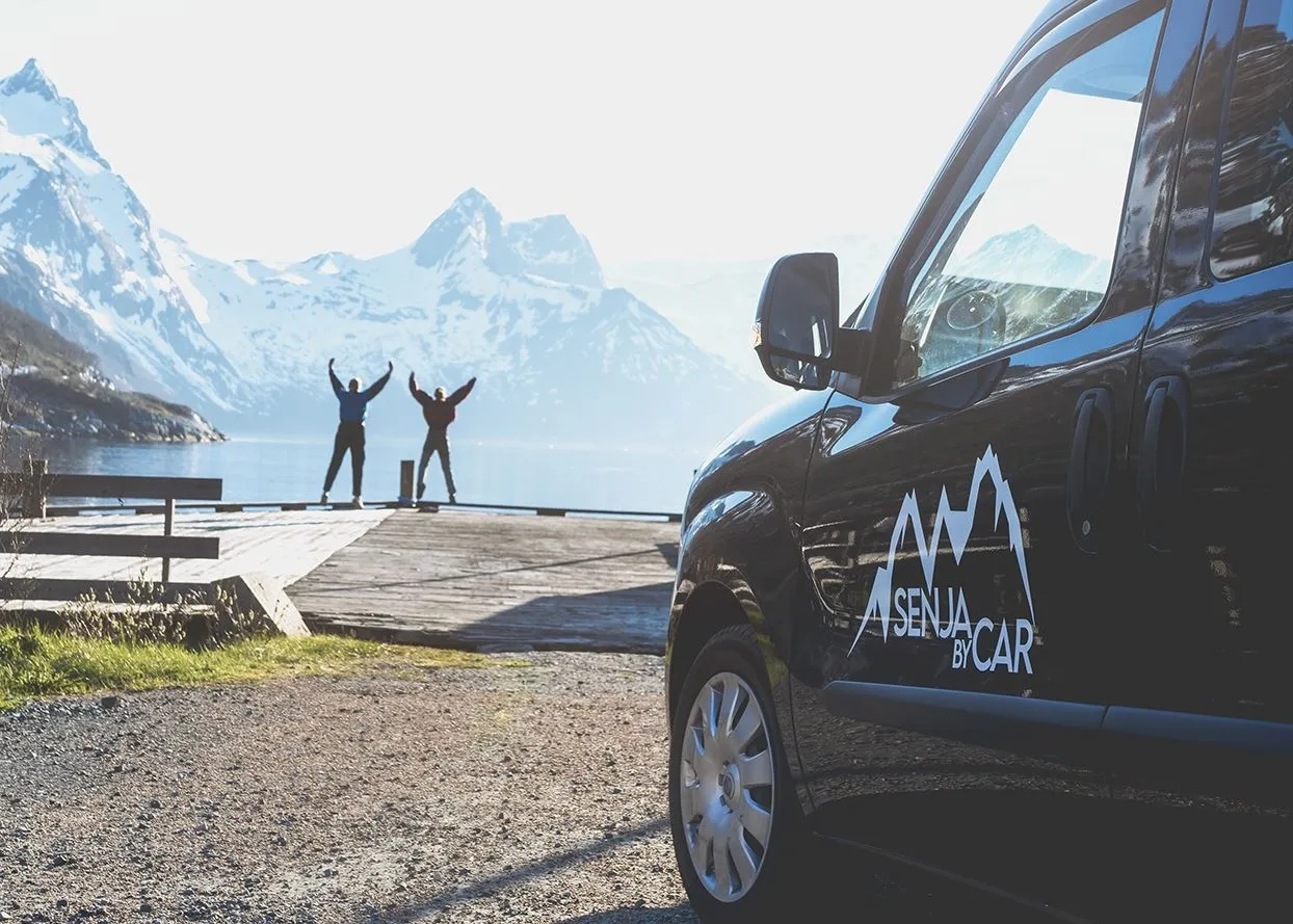 Two people looking at mountains in front of car